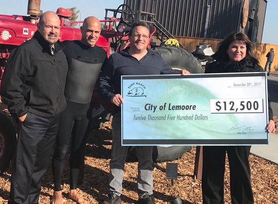 Surfing legend Kelly Slater (second from left) presents a $12,500 check to city officials, including Mayor Ray Madrigal, City Manager Nathan Olsen, and Community Development Director Judy Holwell.